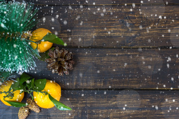 Mandarin fruits, Christmas tree branches and cones on a rustic background in the snow. Christmas holidays