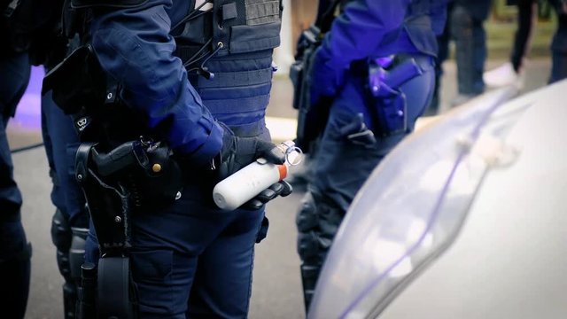 French Police officers securing the zone in front of the yellow vests movement protesters on Quai des Bateliers street woman officer with tear gas bottle ready to use it 