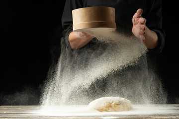A professional chef in a professional kitchen prepares dough from flour to cook Italian pasta,...
