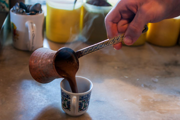 Pouring fresh  Turkish coffee into a cup