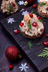 Canape shaped as a Christmas tree with pate garnished with pomegranate and dill surrounded by Christmas decorations