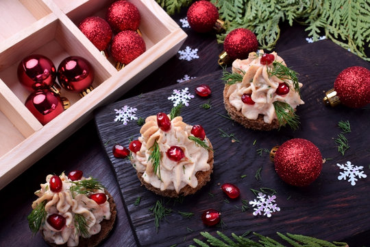 Canape shaped as a Christmas tree with pate garnished with pomegranate and dill surrounded by Christmas decorations