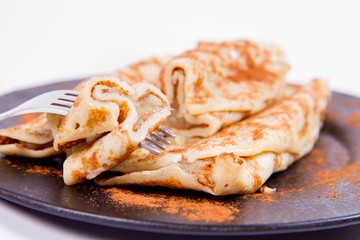 Pancakes stuffed with braised apples sprinkled with cinnamon eaten with a fork