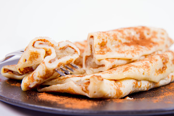 Pancakes stuffed with braised apples sprinkled with cinnamon eaten with a fork