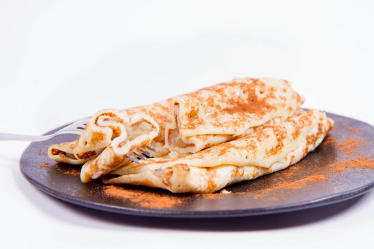 Pancakes stuffed with braised apples sprinkled with cinnamon eaten with a fork