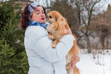 Christmas, winter holidays concept. Beautiful plus size woman with red pekingese dog at park. Love and care for pets