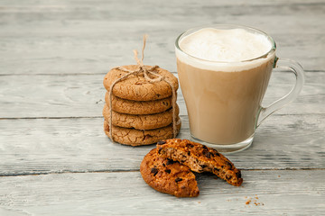 Cup of coffee with American cookies on grey wooden background