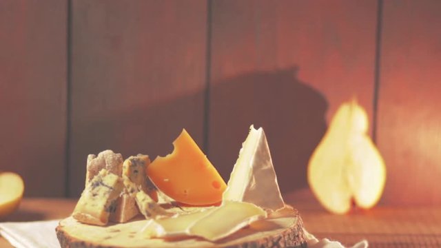 Various type of cheese and pieces of pear on wooden boards. Blue cheese, camembert and hard cheese on wooden stand. Assortment of cheese and ripe pear