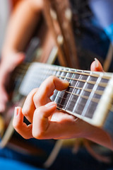 Closeup of young woman hand playing on black acoustic guitar
