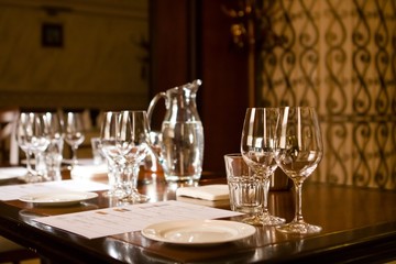 wineglasses and glass jugs on a table ready for wine testing in a restaurant