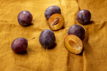 Fototapeta premium Fresh plums on yellow fabric