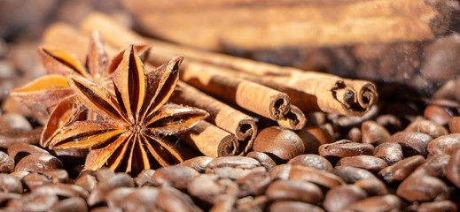 Coffee beans background with different spices: anise stars and cinnamon sticks. Christmas concept.