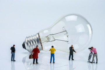 Miniature figures near a light bulb, conceptual image