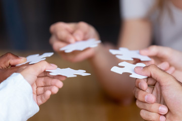 Diverse multinational businesspeople or best friends holding white pieces of puzzle jigsaw, close...