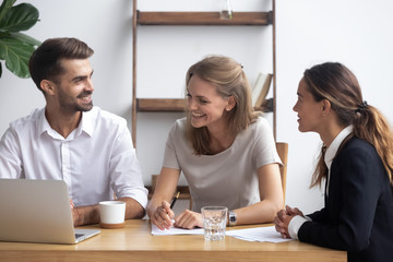 Diverse businesswomen businessman sitting at office desk use laptop reviewing documents. Cheerful workmates take brake joking or discuss project share thoughts business ideas feel good and satisfied