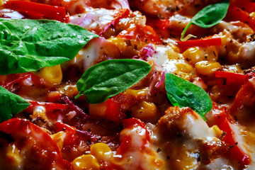 Pizza topped with ham, tomatoes, spices, fresh basil delicious pizza. Home made food. Close up.