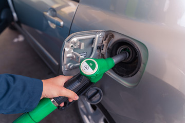 Fuel pistols at European Petrol station. Woman's hand  putting 95 E5 fuel  green pistol to the fuel...
