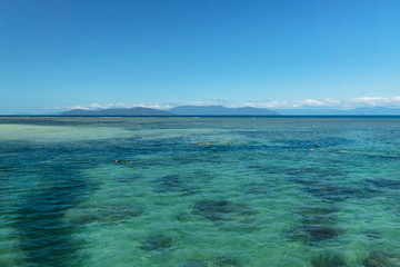 Transparent turquoise water at Green island with tourists doing snorkelling, Great Barrier Reef near Cairns in Australia