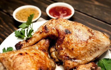 Chicken legs in a plate with mustard and ketchup on a wooden background.
