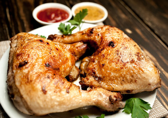 Chicken legs in a plate with mustard and ketchup on a wooden background.