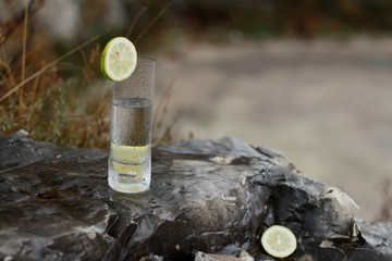 Un vaso de limonada sobre una roca, rodajas de limon