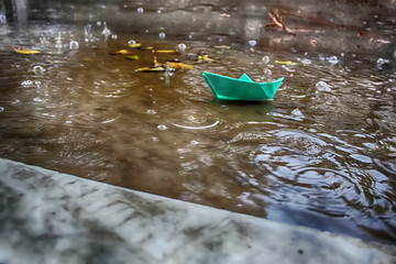 Weather in Israel, Winter. Paper Boat (Origami Ship) sails in a puddle during the rain, circles on...