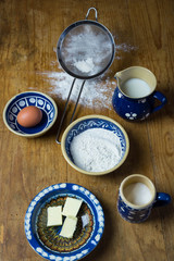 Baking background top view. Making sweet bun or bread dough. Cooking ingredients for pastry on wooden board with dough, egg, yeast, milk, flour. Culinary classes or recipe concept