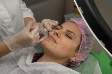 Obraz na płótnie Canvas A woman getting cosmetic injection in beauty clinic. Cosmetic procedure for facial rejuvenation. The beautician doing a injection anti-wrinkles. Plastic surgery.