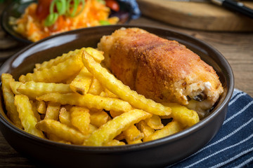 Fried chicken breast stuffed with mushrooms and cheese wrapped in ham served with fries and salad.