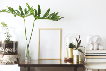 The stylish interior with mock up poster frame, plants, books, leafs and elephant sculpture. The...