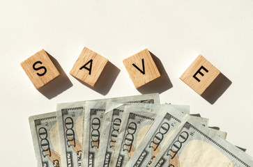 Save spelled in letter tiles with one hundred dollar bills