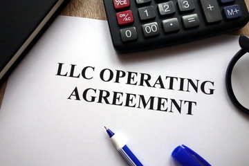 LLC operating agreement, pen, glasses and calculator on   desk