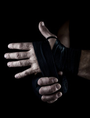 man wraps his hands in black textile bandage for sports