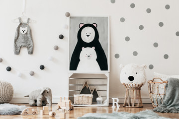 Stylish scandinavian child room with mock up photo poster frame on the pattern wall, boxes, teddy bear and toys. Cute modern interior of playroom, white walls, wooden accessories and colorful toys.