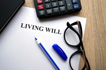Living will document, pen, glasses and calculator on desk