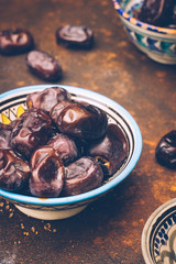 Dried dates in an oriental ceramic bowl on a dark background. Ramadan snacks