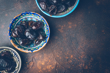 Dried dates in an oriental ceramic bowl on a dark background. Ramadan snacks