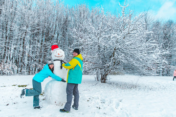 Fototapeta na wymiar couple making snowman in frozen winter day