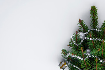 Evergreen little christmas tree lies on white background. Decorated with little gift, silver baubles and chain. Copy space for text.
