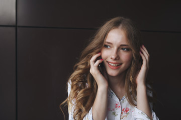 Fototapeta premium Portrait of excited beautiful girl looking at mobile phone and smiling