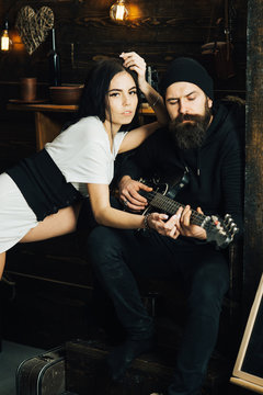 Song for her. Bearded man play guitar to sexy woman. Man guitarist play for girlfriend. Couple in love enjoy music. Romantic couple of brutal man and sensual woman. Rock style couple of lovers