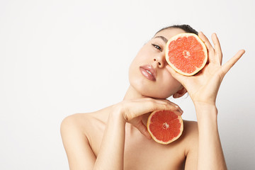 Portrait of young woman with an orange. Detox concept.