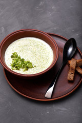 Delicious broccoli cream soup in a beautiful clay bowl. Soup-puree and small toasts of rye bread. Exquisite black dining spoon and a napkin of coarse cloth. Gourmet restaurant lunch.