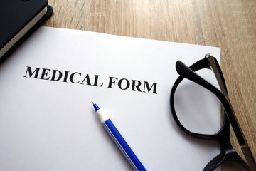 Medical form, pen and glasses on desk