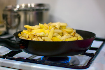 potatoes are fried on a gas stove. soft focus