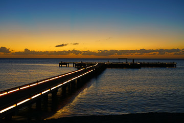 Fototapeta na wymiar Sunset view of a lighted pier dock on the Caribbean Sea