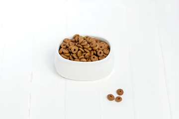Obraz na płótnie Canvas Dry cat food poured into a white bowl on a white background.