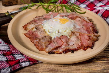 Plate of breakfast with fried eggs, bacon and bread.