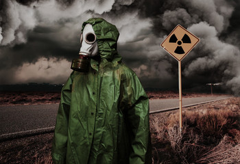 Man in gas mask with radiation area caution sing. Nature protection concept