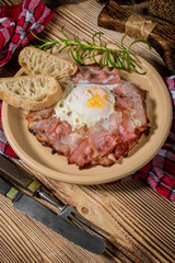 Plate of breakfast with fried eggs, bacon and bread.